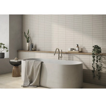 Badrum med badkar, blandare, handduk, hylla och väggplattor