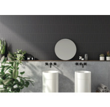 Badrum med mörka väggplattor, två handfat, rund spegel och dekoration