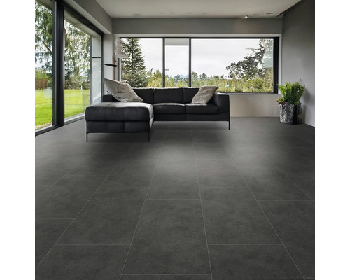 Modernt vardagsrum med storformatiga grå golvplattor och en svart lädersoffa