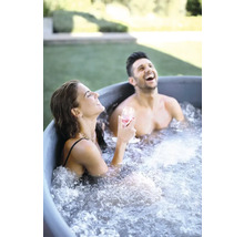 Två personer kopplar av och skrattar i ett badkar i trädgården