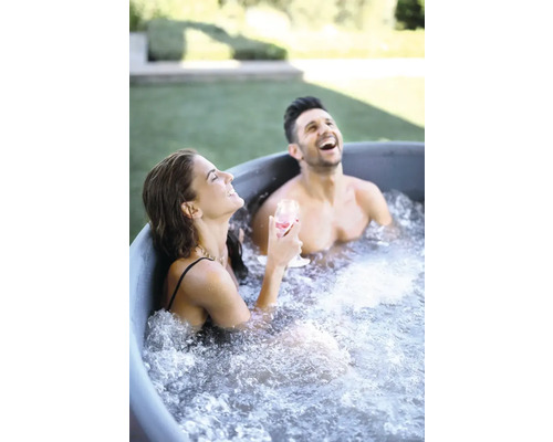 Två personer kopplar av och skrattar i ett badkar i trädgården