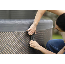 Person som fäster locket på ett spabad med spännen