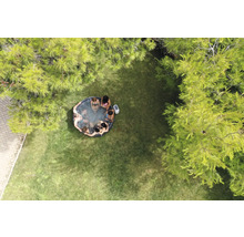 Flygfoto av en trädgård med en uppblåsbar bubbelpool där flera personer sitter.