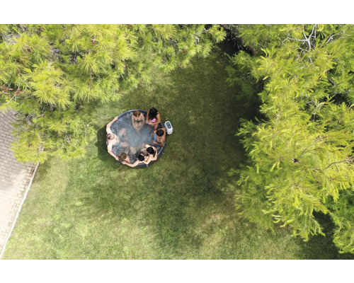 Flygfoto av en trädgård med en uppblåsbar bubbelpool där flera personer sitter.