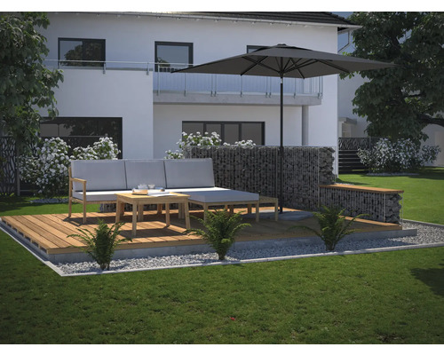 En modern terrass med trädäck, grå loungeset, parasoll och gabionmur i trädgården.