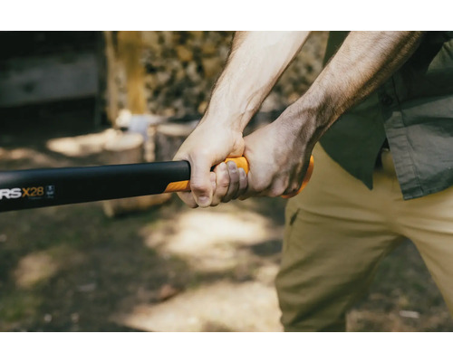 En person håller i en klyvyxa från Fiskars för att hugga ved.