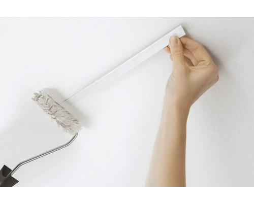 En person använder en färgroller med teleskopskaft för att måla en vägg.