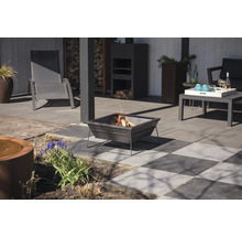 Terrasscen med eldstad, trädgårdsmöbler och dekorativa element.