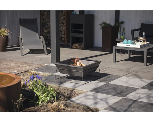 Terrasscen med eldstad, trädgårdsmöbler och dekorativa element.
