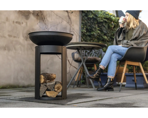 Eldskål med ved och sittande person utomhus