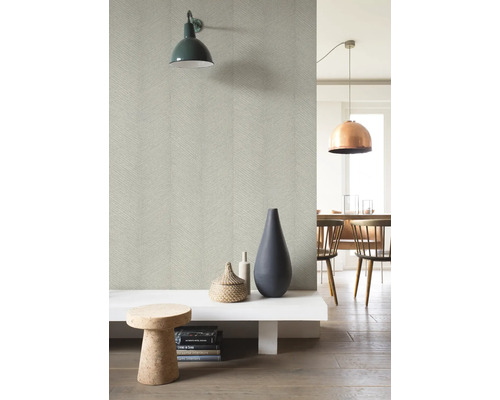 Ljust rum med mönstrad tapet, vägglampa, dekorationer och matplats i bakgrunden