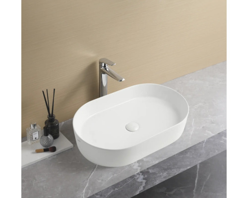 Oval tvättställ med blandare på en bänkskiva i badrummet.