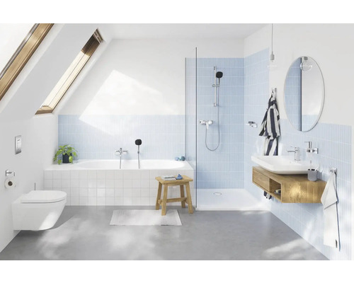 Modernt badrum med badkar, dusch, handfat och toalett under ett takfönster.