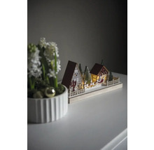 Dekorativ julscen med hus, träd och jultomtens släde