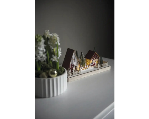 Dekorativ julscen med hus, träd och jultomtens släde