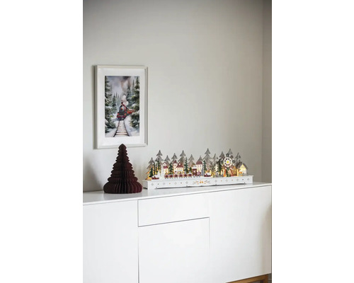 Dekorativ julby med tåg på en vit byrå med en bild av ett tåg på väggen.