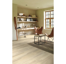 Ljust rum med trägolv, hyllor, dekoration och två läderfåtöljer