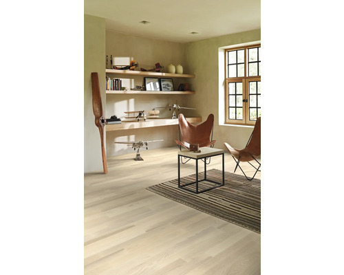 Ljust rum med trägolv, hyllor, dekoration och två läderfåtöljer