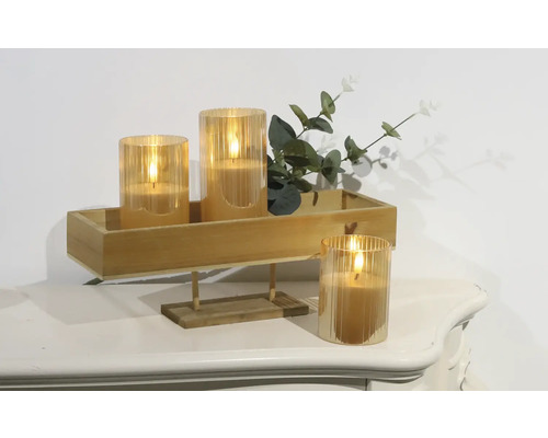 Dekorativa LED-ljus i glasbehållare på en träbricka med växter på ett bord