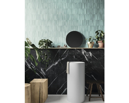 Badrum med tvättställspelare, väggplattor i marmorlook och ljusa, avlånga väggplattor