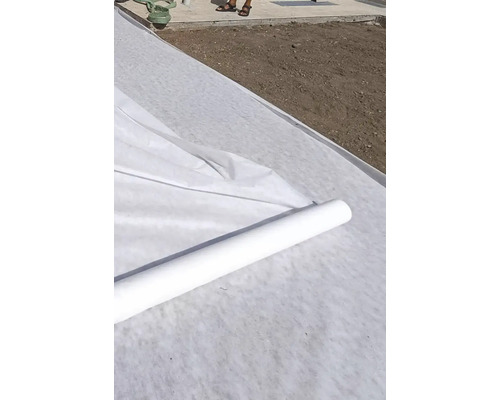 Fiberduk för gräsmatta på rulle rullas ut på ett förberett område.