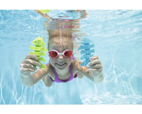 Flicka dyker med fiskleksak i poolen