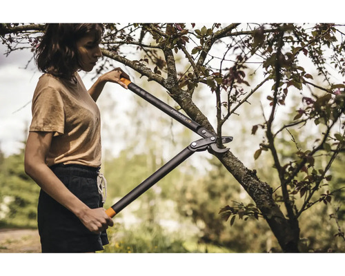 En kvinna klipper en gren med en grensax av märket Fiskars.