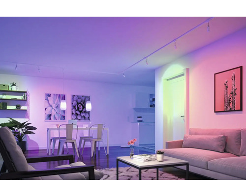 Vardagsrum med soffa, matbord, stolar, hyllor och LED-belysning