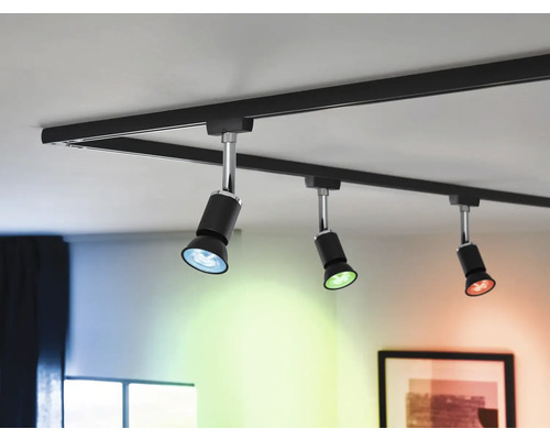 Svart skensystem med tre spotlights i taket som avger blått, grönt och rött ljus.