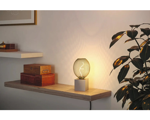 Dekorativ bordslampa med sfärisk lampskärm och fyrkantig bas på en hylla