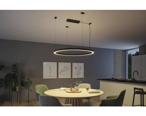 Matsal med runt träbord och rund LED-pendellampa ovanför.
