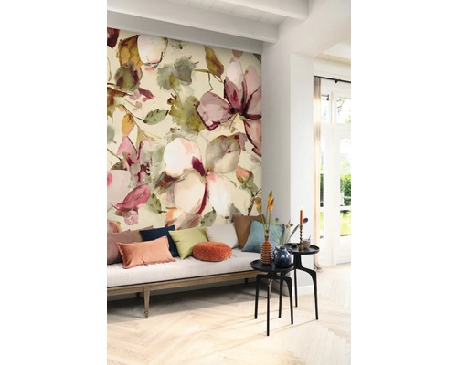 Vardagsrum med blommig tapet, soffa med kuddar och sidobord.