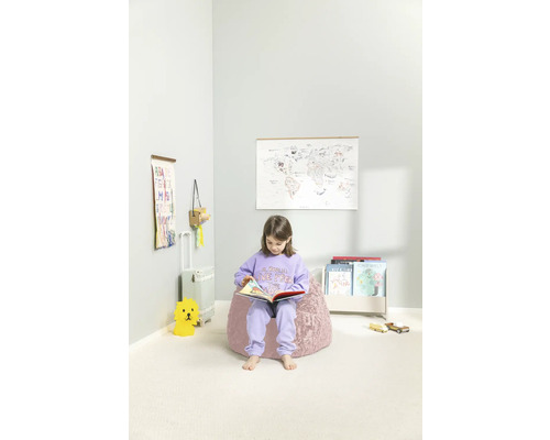 Barn sitter på en sittsäck och läser en bok i ett barnrum med en världskarta, hylla och leksaker