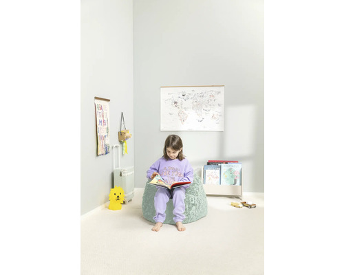 Flicka läser bok på en sittsäck i ett ljust barnrum med en världskarta på väggen