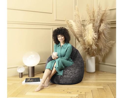 En kvinna sitter i en grå sittsäck i ett ljust rum.