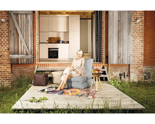 Scen med en kvinna som sitter på en sittsäck utomhus framför ett hus