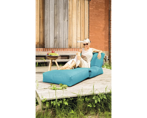 Kvinna kopplar av på en turkosfärgad trädgårdsbädd på en träterrass utomhus