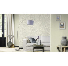 Vardagsrum med soffa, golvlampa och blommig tapet för en ljus atmosfär