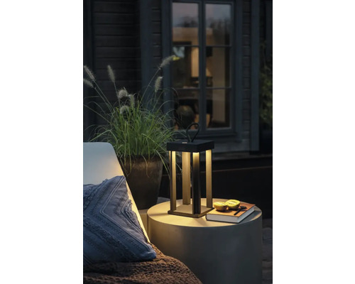 Miljöbild med en bordslampa, ett sidobord och en kudde på en terrass