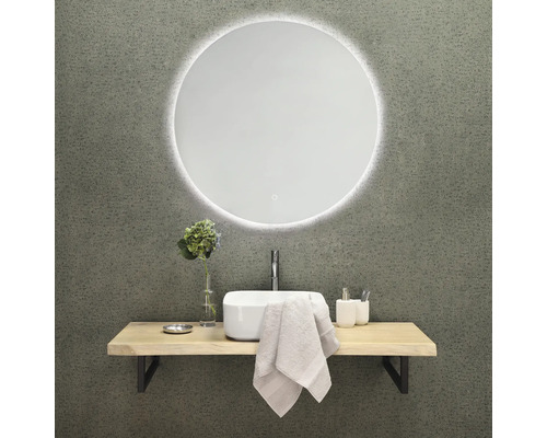 Badrumsdesign med rund spegel, handfat, armatur och hylla