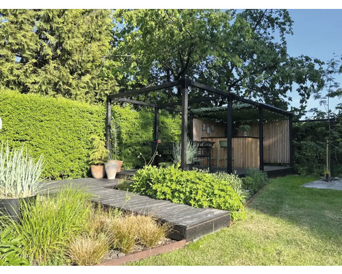 Trädgård med växter, gångväg och pergola med bar