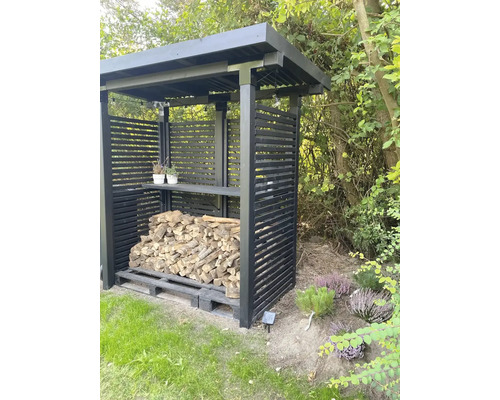 Vedförvaring med horisontella lameller och trä på en pall i trädgården