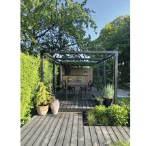 Stilfull trädgård med trädäck, pergola, matbord och plantering.