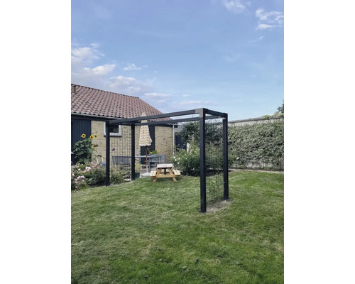 Metallpergola med sittgrupp på gräsmatta i trädgården