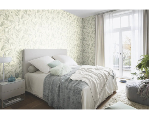 Sovrum med bladmotiverad tapet, säng och nattduksbord