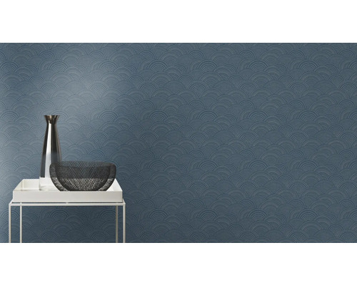 Närbild av en blå tapet med ett upprepande halvcirkelformat mönster, tillsammans med en vas och en skål på ett bord.