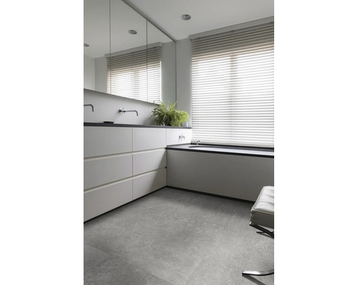 Modernt badrum med handfat, spegel, fönsterjalusier och klinkergolv.