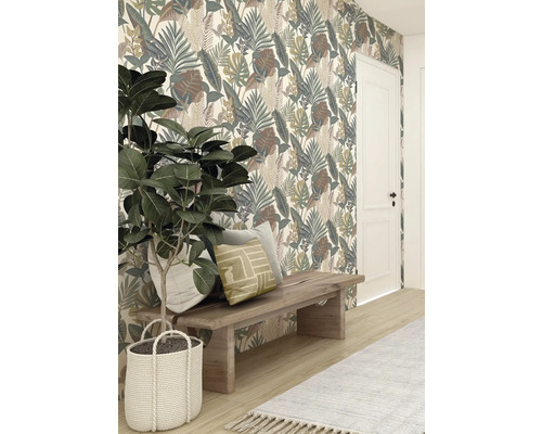 Dekorativ tapet med bladmönster bakom träpall med kuddar och krukväxt i flätad korg