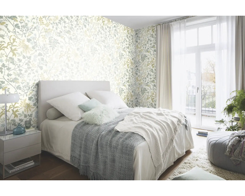 Sovrum med blommönstrad tapet, säng och överkast