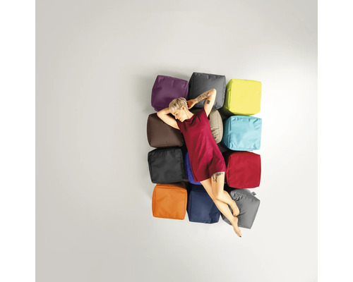 Kvinna ligger avslappnad på en stapel med olika färgade sittkuber
